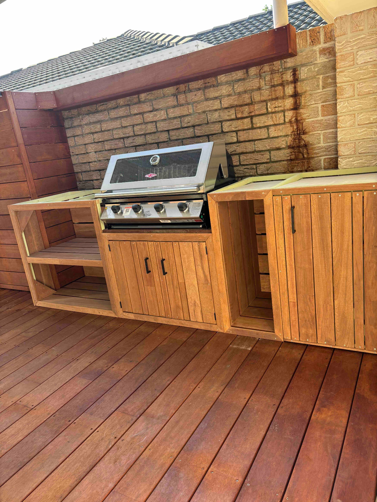 Built-in hardwood outdoor BBQ kitchen with a grill set into the bench