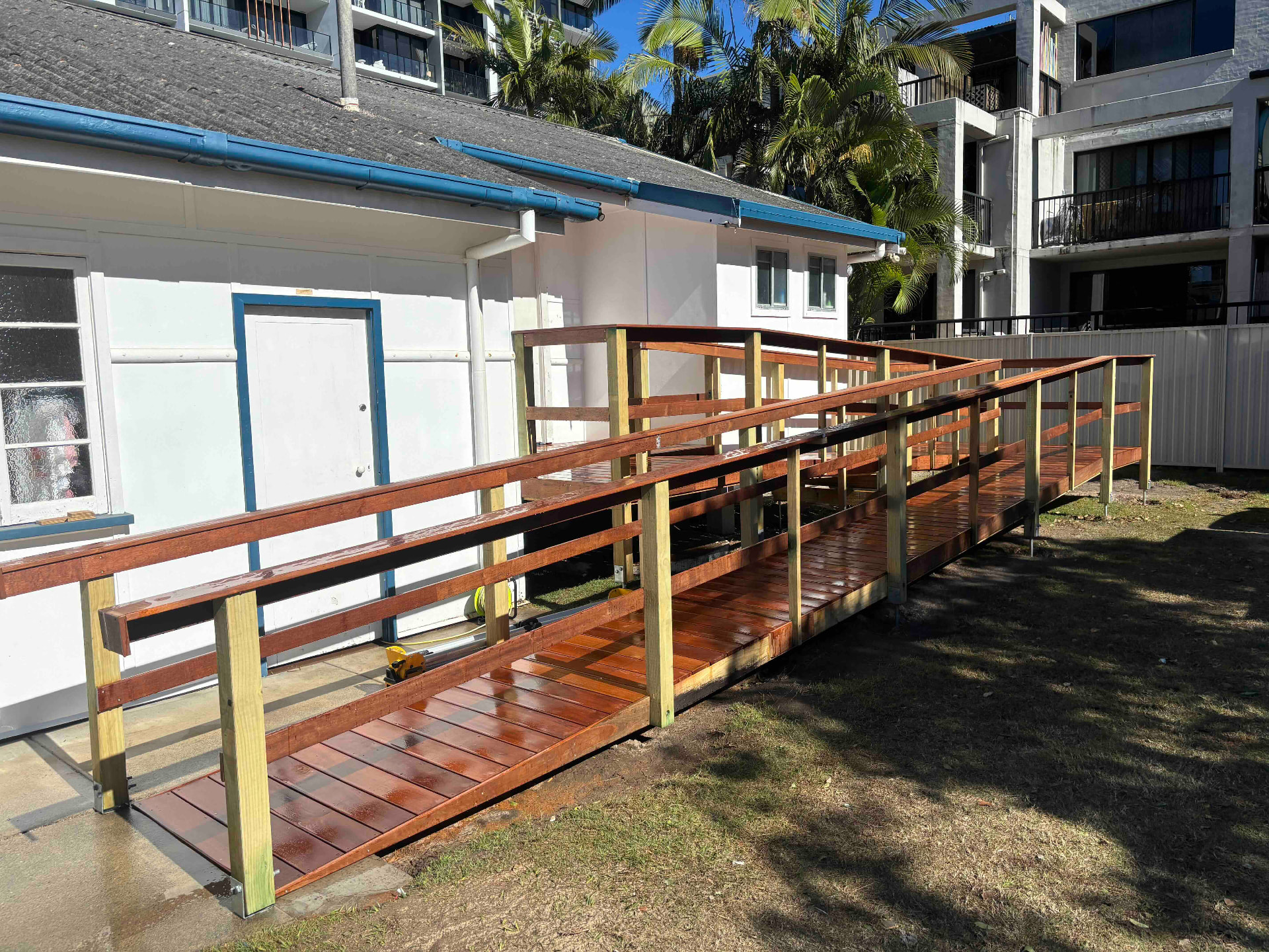 Hardwood disability access ramp with timber handrails leading to a community building entry
